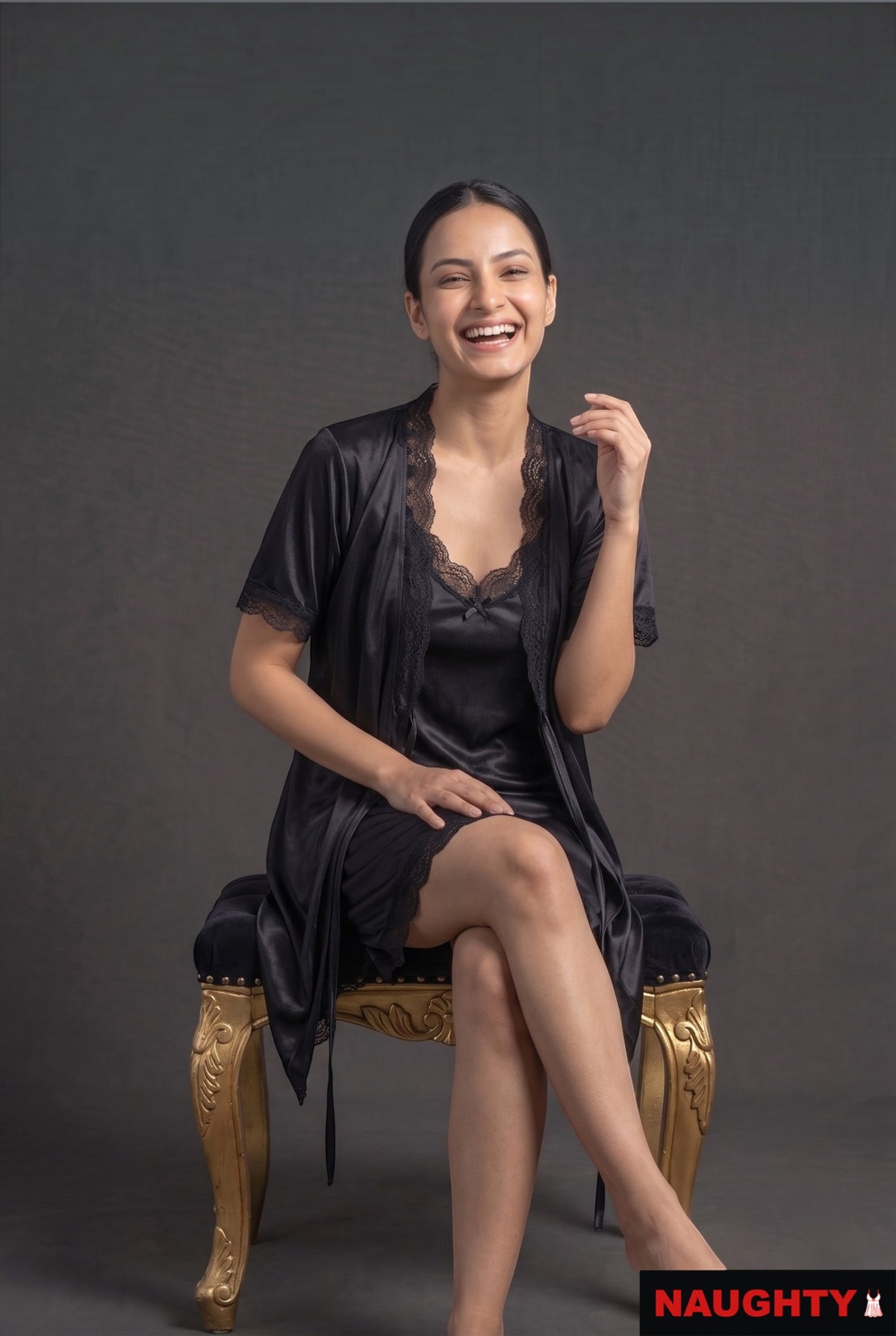 Naughty black silky satin 2-piece lingerie set with lace trim worn by a smiling woman sitting on a gold stool