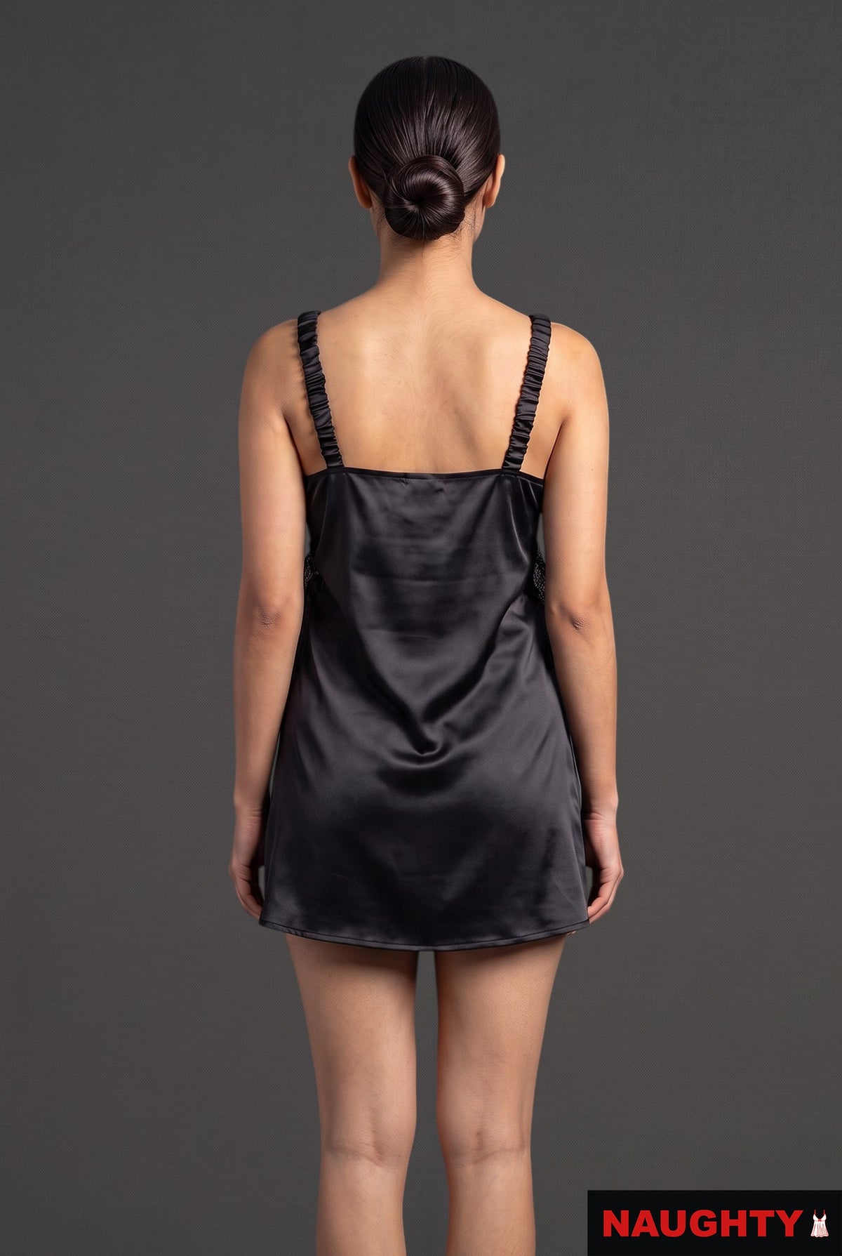 Back view of a woman wearing a Naughty black silky satin nightdress with gathered straps against a grey background